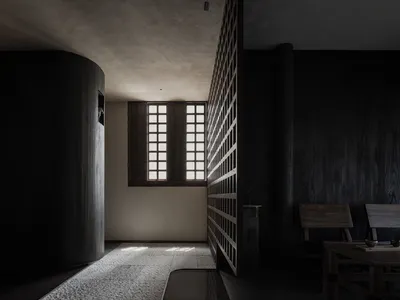 Dimly lit hallway with a wooden door, two chairs, and a dining table, creating a cozy and mysterious atmosphere