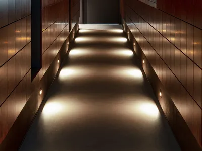 A dimly lit hotel hallway with red brick walls, featuring two doors on either side and an air of elegance and sophistication