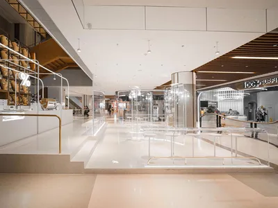 Empty retail space with white walls, tables, and chairs, well-lit with possible natural and artificial light