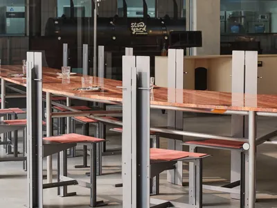 Industrial restaurant with a long wooden table and metal chairs, well-lit with natural and artificial light