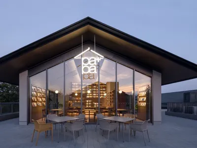A modern restaurant interior with a large dining area, tables, chairs, books, and a cozy atmosphere