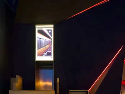 Modern hotel lobby with black and gold decor, two elevators, and a sophisticated atmosphere