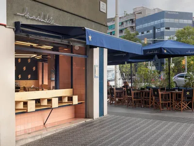 Outdoor cafe with a mix of wood and metal elements, umbrellas, and seating areas for patrons