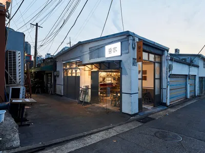 A well-lit Asian restaurant with a white exterior, glass door, and wooden furniture, creating a comfortable dining atmosphere