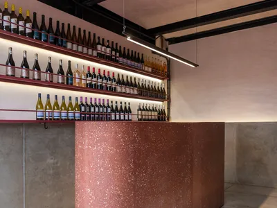 A sophisticated interior design showroom featuring a marble countertop with a display of wine bottles in various positions