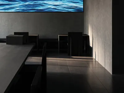 A calm restaurant with a large screen displaying a waterfall scene, surrounded by chairs and tables