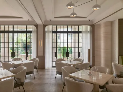 Sophisticated restaurant interior with white chairs and tables, potted plants, and varied chair styles