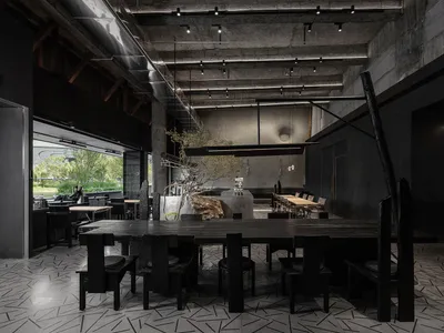 空蕩蕩的現代餐廳內部，配有大型餐桌、椅子、盆栽、混凝土牆面與柔和燈光