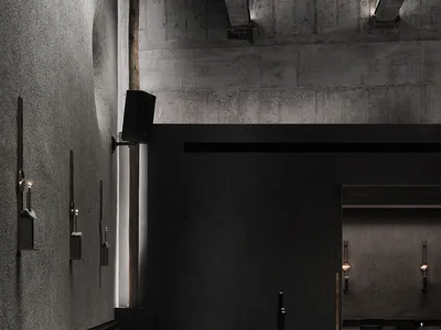 Empty modern restaurant with black walls, dining tables, and candles creating a warm atmosphere
