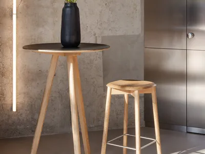 A cozy living space with a wooden table, two chairs, and a black vase filled with flowers, creating a warm and inviting atmosphere