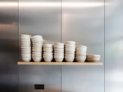 A modern kitchen with a metal wall displaying a collection of plates in various sizes and shapes, arranged in an organized and visually appealing manner
