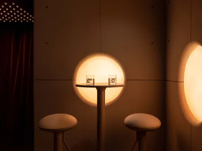 Cozy seating arrangement with two round tables and chairs, illuminated by circular lights creating a warm and inviting atmosphere