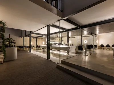 A lively modern restaurant interior with a large dining area, brick and concrete flooring, and multiple tables and chairs