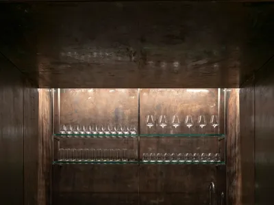 深色調廚房配備黑色冰箱冷凍櫃，酒杯點綴其中，營造溫馨舒適的氛圍