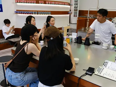 休閒餐廳場景，設有吧台與酒吧區，包含杯子、酒瓶，以及一名坐在吧台使用手機的男子