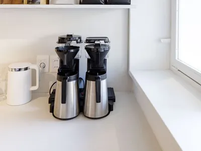 A well-stocked kitchen counter with coffee makers, cups, and coffee beans, creating a cozy atmosphere for enjoying a warm cup of coffee