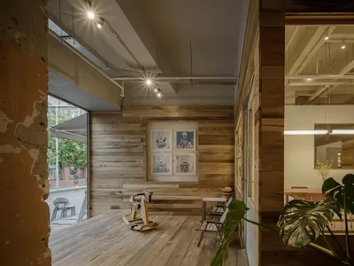 A well-designed showroom with a large wooden floor and various pieces of furniture, including chairs and a dining table, creating a warm and inviting atmosphere