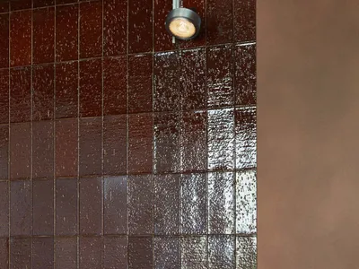 Warm bathroom with red brick walls, brown tile floor, and two overhead lights