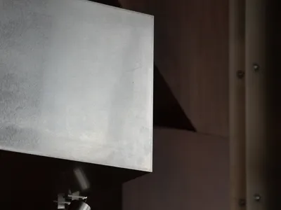 A modern restaurant interior wall with a steel surface, a light fixture, and minimal decoration