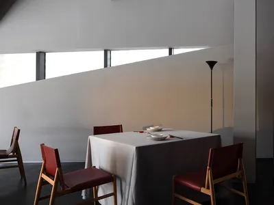 餐廳區配有兩把椅子與桌巾，桌上擺放花瓶與三個碗