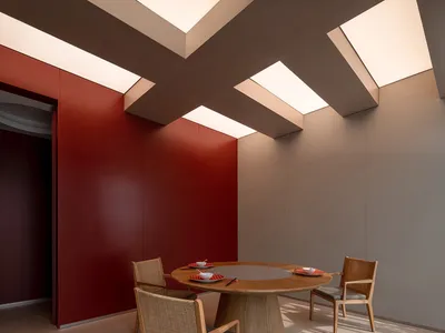 A cozy dining area with a wooden table, two chairs, plates, and cups, surrounded by red-painted walls