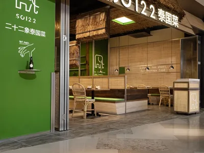 A modern Asian restaurant with a thatched roof and green exterior, featuring dining tables and chairs in a comfortable atmosphere