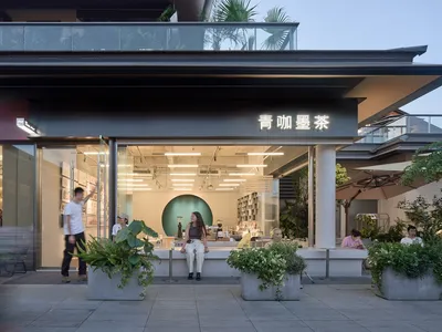 A modern Asian restaurant with a welcoming atmosphere, featuring a dining table, potted plants, and well-lit surroundings
