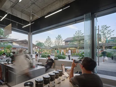 A bustling restaurant and store with a mix of wood and metal elements, potted plants, and natural lighting