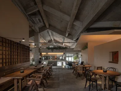 開放式餐廳內部，多張餐桌、椅子、盆栽植物，以及磁磚地板營造現代設計風格