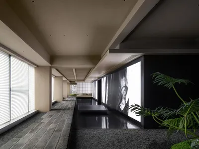A calm and quiet hallway with a tiled floor, a large picture on one wall, and two potted plants adding greenery