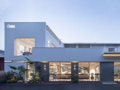 A modern living area with a dining table, chairs, potted plants, and clean lines, well lit with natural and artificial light