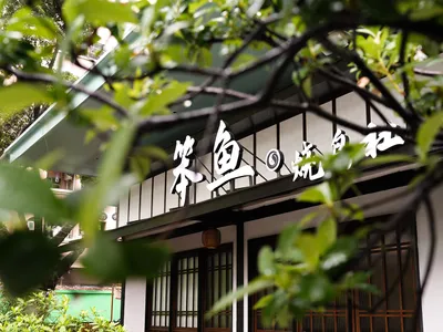 Modern Asian restaurant with a white exterior, black roof, and outdoor seating area with chairs