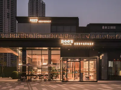Modern Asian restaurant with a sleek glass exterior, dining tables, chairs, and umbrellas inside
