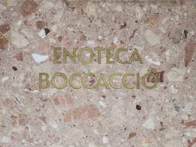 A modern hotel lobby with a marble wall and gold sign, featuring a sophisticated and welcoming atmosphere