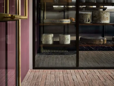 A well-organized cheese shop with a glass display case showcasing a variety of cheeses in different shapes, sizes, and colors