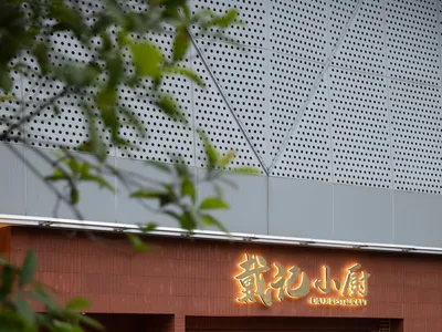 A welcoming Asian restaurant entrance with a wooden door, brick walls, and comfortable seating area