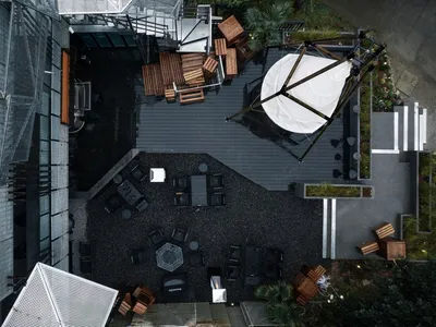 A modern restaurant space with black furniture, umbrellas, and a mix of seating areas