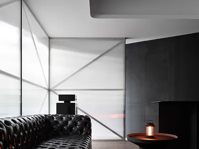 Modern living room with black leather couches, white panel walls, and a fireplace, featuring a clean and minimalist aesthetic