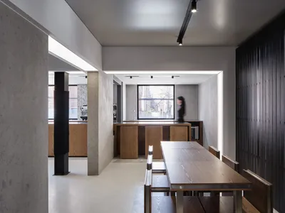 A modern cafe with a large wooden dining table surrounded by chairs, creating a warm and inviting atmosphere