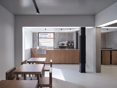 Modern restaurant interior with open seating area, dining tables, chairs, and coffee machines