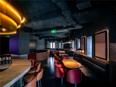 Modern restaurant interior with black and red elements, multiple chairs, and a dining table, emphasizing comfort and functionality
