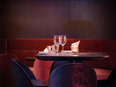 現代餐廳內部，設有兩張餐桌、椅子、酒杯與餐巾，營造時尚而溫馨的氛圍