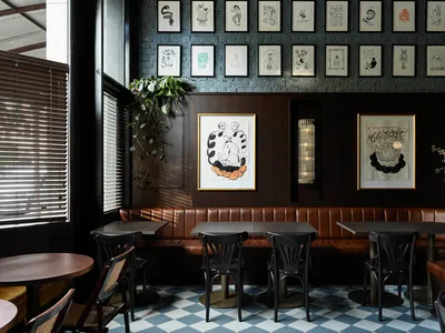 A restaurant dining area with multiple tables and chairs, walls adorned with pictures, creating an inviting atmosphere for meals and socializing