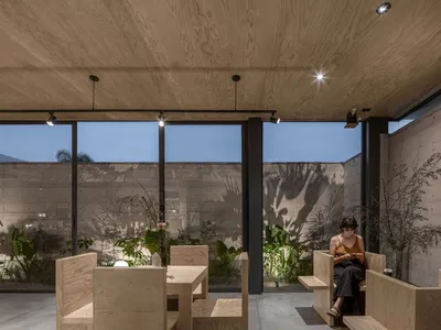 Cozy restaurant space with wooden paneling, potted plants, and comfortable seating areas