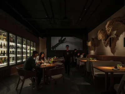 熱鬧的室內餐飲空間，設有多張桌子和椅子，人們享用餐點並交談，桌面擺放瓶子