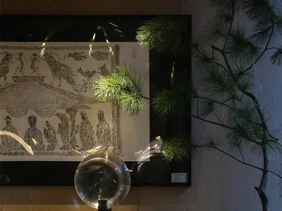 一個帶有石桌、玻璃碗和數盆植物的客廳區域，搭配三尊裝飾人物