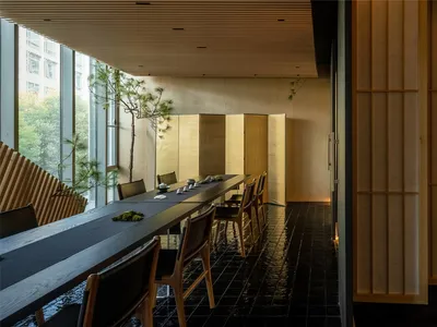 溫馨亞洲餐廳餐廳區，配有長形木桌與椅子，擺放碗盤、杯子與湯匙，周圍環繞現代木質元素與溫暖裝飾