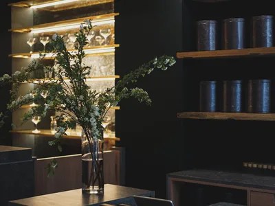 An elegant showroom with a black table featuring a flower vase and wine glasses, surrounded by additional tables in the background