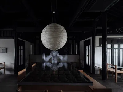 A black and white room with a glass box interior, featuring two chairs and a dining table, conveying a sense of calmness and tranquility