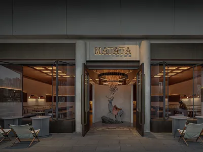 A spacious restaurant interior with multiple dining tables and chairs, creating a warm and inviting atmosphere